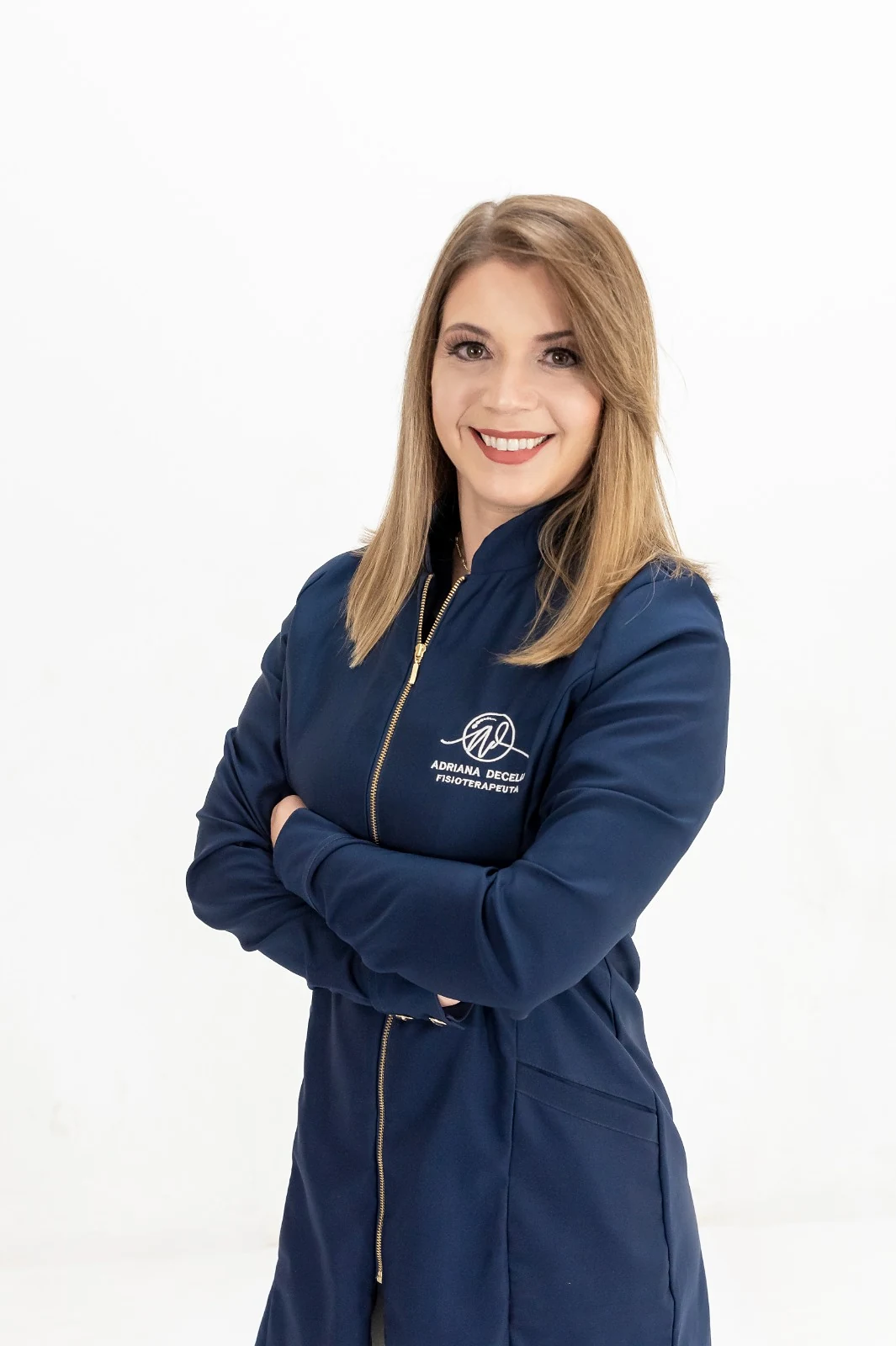 Adriana Decelli, fisioterapeuta da Clínica Humaniza, de jaleco azul-marinho e braços cruzados, sorrindo